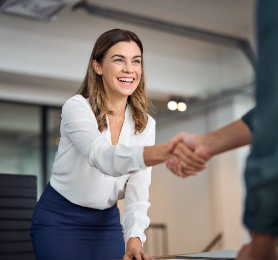 Businesswoman smiling while shaking hands in office at Pioneer Business Brokers.