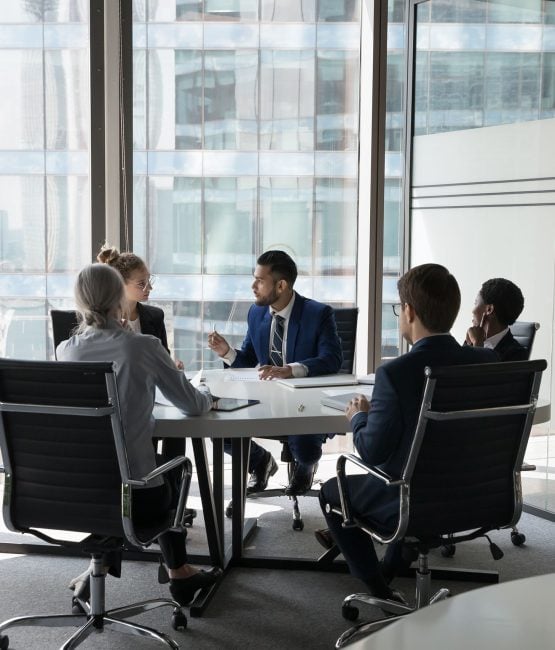 Business team discussing strategy around conference table at Pioneer Business Brokers.