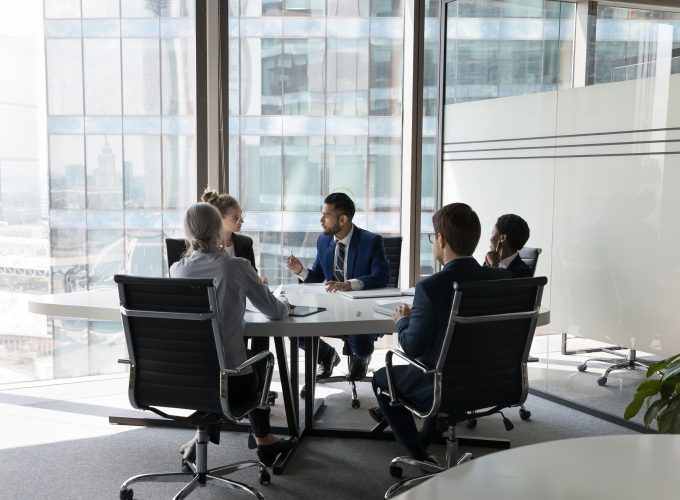 Business team discussing strategy around conference table at Pioneer Business Brokers.