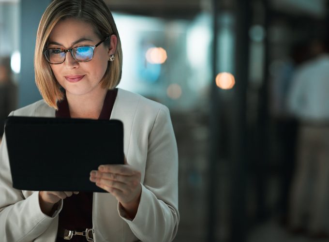 Businesswoman wearing glasses using a digital tablet at Pioneer Business Brokers office.
