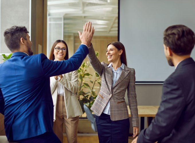 Colleagues celebrating success with high five during meeting at Pioneer Business Brokers.