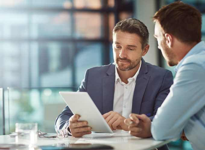 Two businessmen reviewing information on a tablet at Pioneer Business Brokers office.