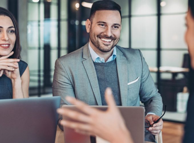 Business professionals smiling during a meeting with laptops at Pioneer Business Brokers.